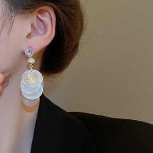 Detail of layered shell petal tassel earrings with a sparkling zircon stud on a model