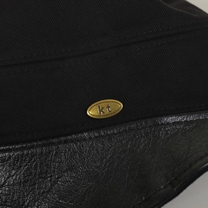 Close-up of cotton fisherman hat featuring leather brim and gold oval metal logo tag