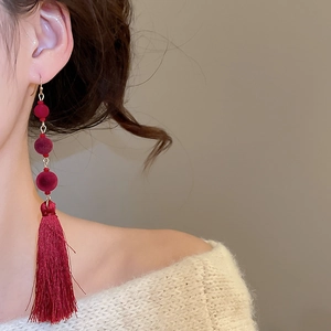 Close-up of red flocked bead earrings with elegant silk fringe on a model
