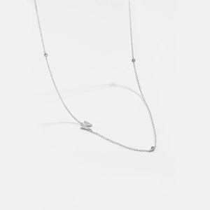 Macro shot of silver clavicle chain with a W-letter pendant and small zircon stones