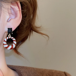 Detail of vintage geometric earrings with red white spiral rings on brown knit sweater