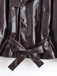 Detail of waist bow tie and stitching on dark brown faux leather short trench jacket