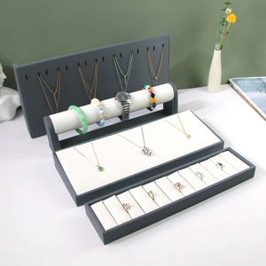 Multi-tier jewelry display stand with necklace hooks and ring tray in grey and white