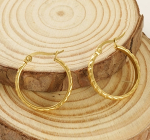 Macro shot of gold-plated hoop earrings with spiral texture on natural wood backdrop