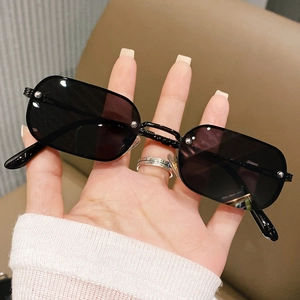 Detail of black rectangular sunglasses featuring silver rivet accents on the lens edges