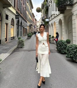 Détail du gilet blanc en tricot à col en V avec boutons en métal et jupe longue plissée
