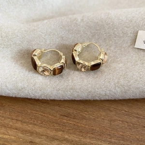 Detailed shot of golden hoop earrings with brown tiger eye heart-shaped stones