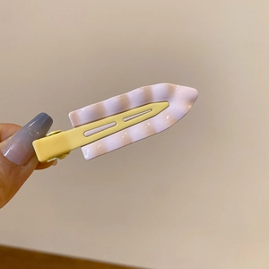 Close-up of a wavy light purple marble pattern hair clip with a yellow alligator base