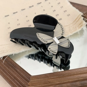 Detailed view of acetate butterfly hair claw clip with rhinestones on a mirror surface