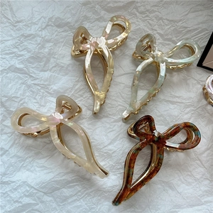 Detailed close-up of acetate butterfly hair claws in white, marble green, and tortoiseshell