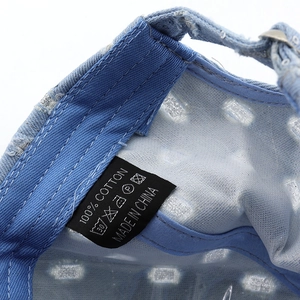 Detail of internal cotton sweatband and wash label on blue distressed denim baseball cap