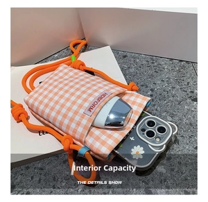 Detail show of small orange checkered crossbody bag interior with phone storage