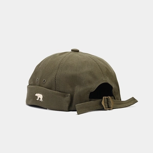 Detail of army green canvas docker hat with bear embroidery and bronze metal buckle