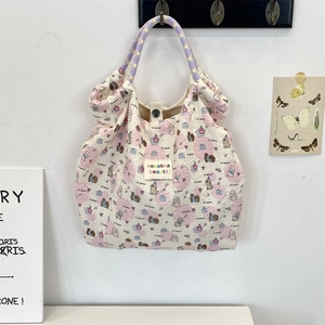 Detail of quilted dog print tote bag with purple checkered woven handles and cloth label