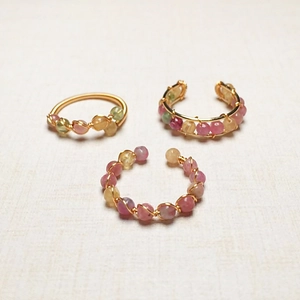 Macro shot of handmade 14K gold-filled wire wrapped rings with pastel tourmaline beads