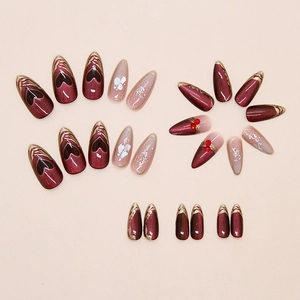 Detail view of dark red heart press-on nails with gold trim and pearl embellishments