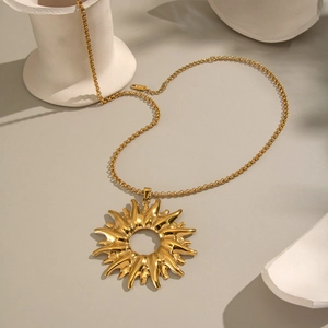Exquisite gold sun pendant necklace in stainless steel on white ceramic props
