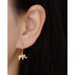 Close-up of golden rhinoceros hoop earring on ear showing the 3D animal pendant detail