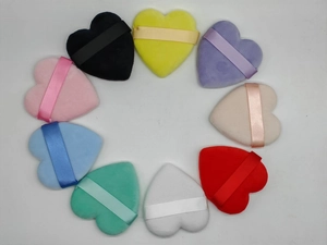Set of 9 heart-shaped makeup puffs in various colors with ribbons on white background