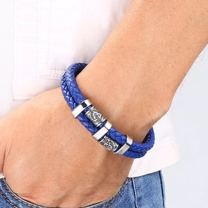 Gros plan d'un bracelet en cuir tressé bleu avec des breloques gravées en argent