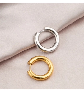 Polished gold and silver hoop earrings resting on smooth light pink silk fabric
