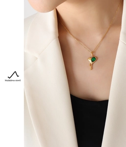 Detail of model wearing a melting heart pendant with emerald zircon in stainless steel