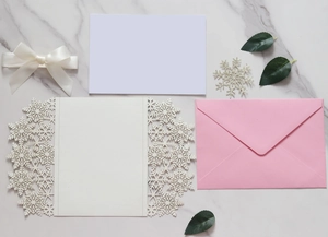 Laser cut snowflake invitation set with white ribbon bow and elegant pink envelope