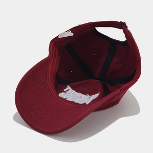 Interior view of burgundy cotton baseball cap showing embroidery and adjustable metal buckle