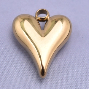 Macro shot of a polished gold heart-shaped stainless steel pendant on textured fabric