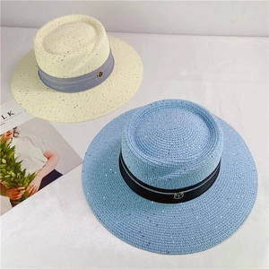 Close-up of woven straw hats with sequins, ribbons and gold T-logo for sun protection