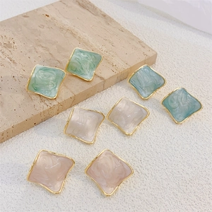 Detail of square geometric enamel earrings with gold-plated edges and marble texture