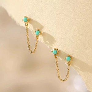 Macro shot of gold S925 silver earrings with turquoise stones and delicate chain tassels