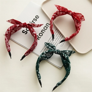 Close-up of three knotted headbands with red and green paisley fabric patterns