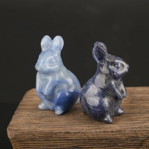Macro detail of two carved natural crystal rabbit figurines on a textured wooden base