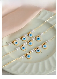Detailed view of evil eye necklaces with pearls and gold beads on a ceramic plate