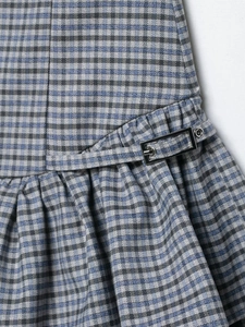 Detail of blue and grey plaid fabric with silver metal buckle and pleated waist design