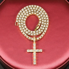 Detailed view of a gold iced-out Cuban chain necklace with sparkling cross pendant