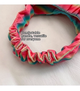 Detail of a rainbow gradient ruffled handle on a shoulder bag with soft pleated fabric