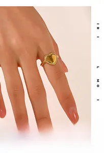 Detail of 18K gold-plated heart ring with beaded edges on a female hand macro view