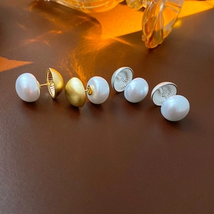 Macro shot of S925 silver pearl stud earrings in gold and silver finish on leather