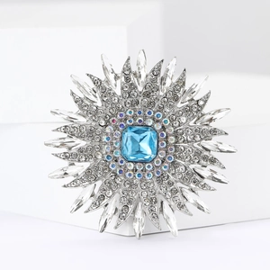 Macro shot of silver sunflower brooch with square blue gemstone and crystal petals