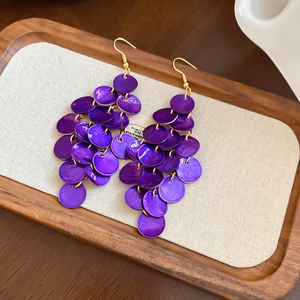 Macro shot of long purple shell tassel earrings with golden hooks and layered discs