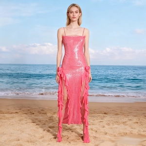 Hot pink sequin evening gown with side ruffles and high slits on a sunny beach background