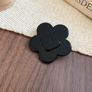 Detail of minimalist black resin flower hair clip with wer wer embossed square center