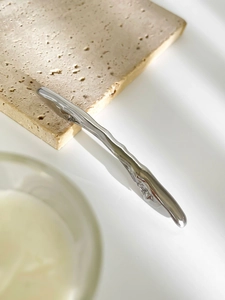 Macro view of wave-shaped silver metallic hair clip with smooth streamlined finish