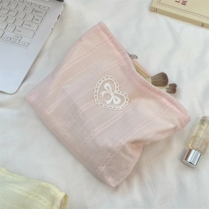 Detailed view of pink knitted cosmetic bag with lace heart and bow detail for makeup storage