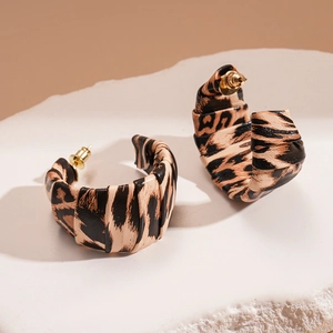 Detail of C-shaped leopard print earrings with pleated leather texture on stone base