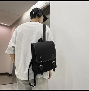 Close-up of black PU leather backpack with white contrast stitching and buckle straps