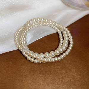 Close-up of elegant triple-layered pearl bracelet with sparkling zircon inlaid metal clasp