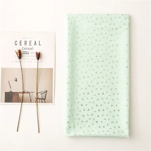 Detail of light green scarf with gold leaf patterns next to a lifestyle magazine